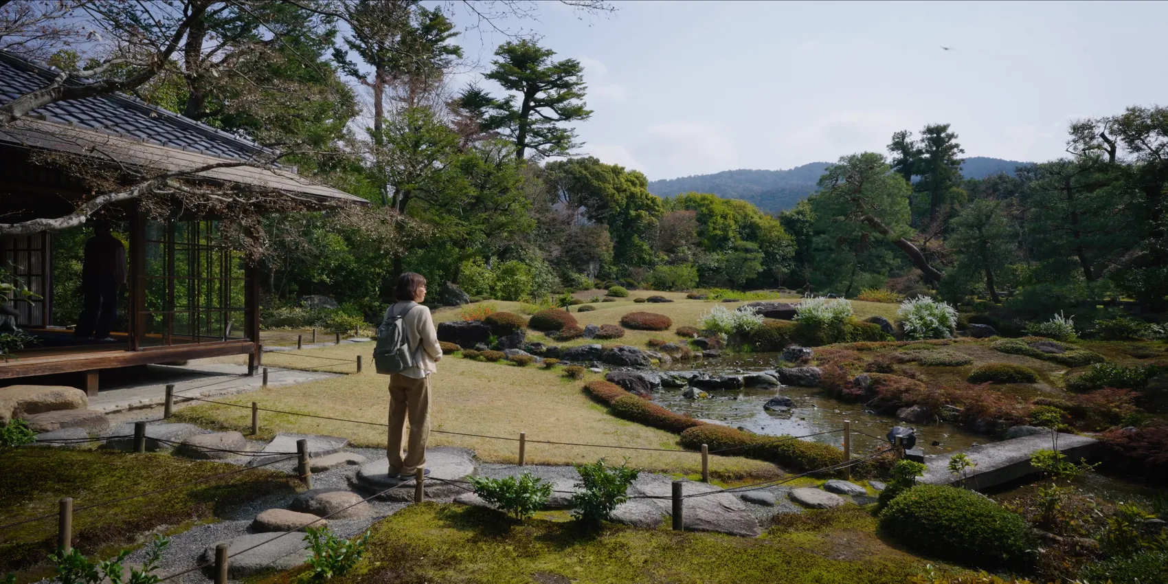 Still from The Reinvention of Kyoto: a visitor looking out over the garden at Murin-an, the hills of Higashiyama behind.
